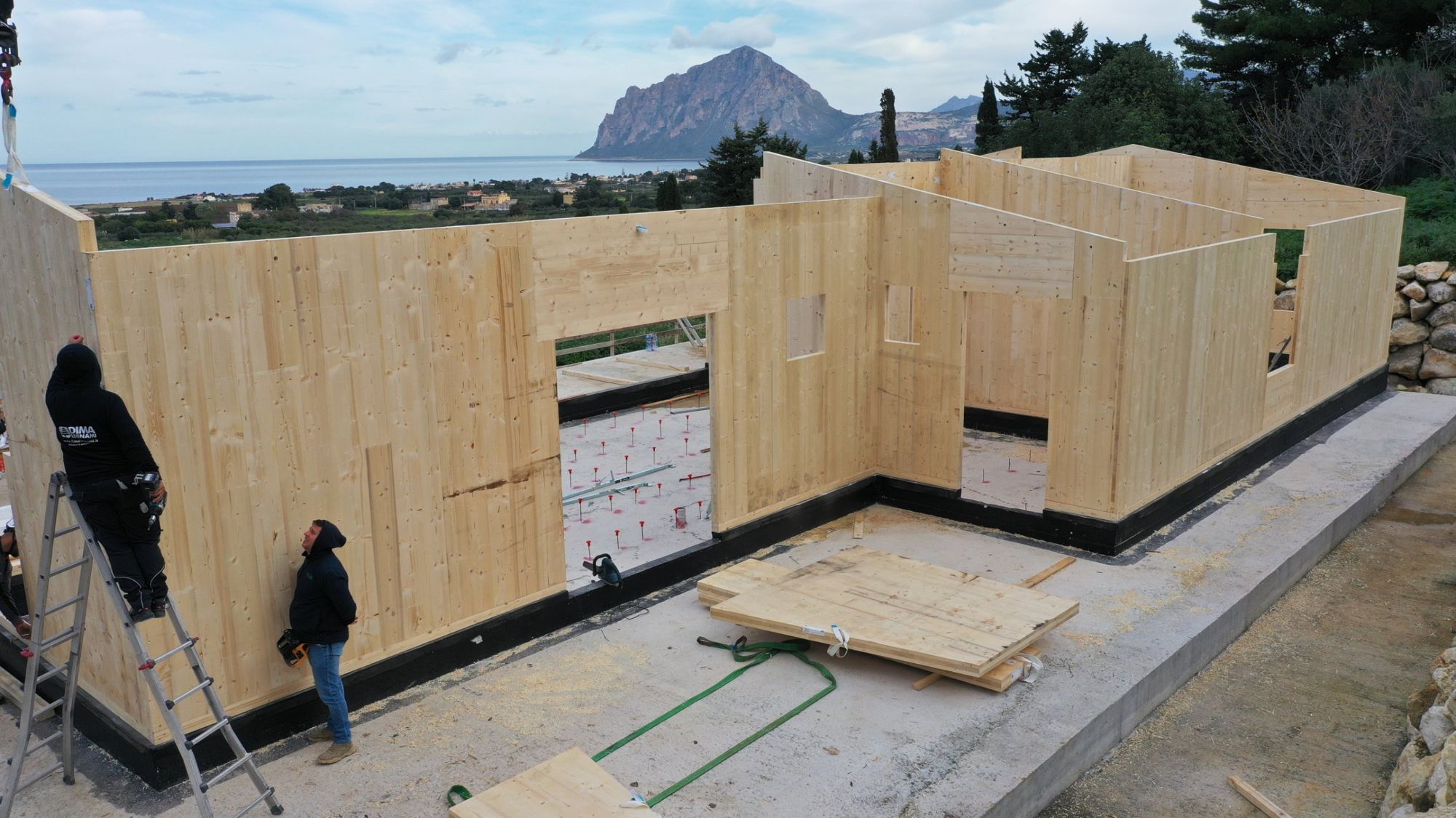 Assembly of the KLH X-Lam wall panels of a house in Sicily, with the sea and mountain in the background